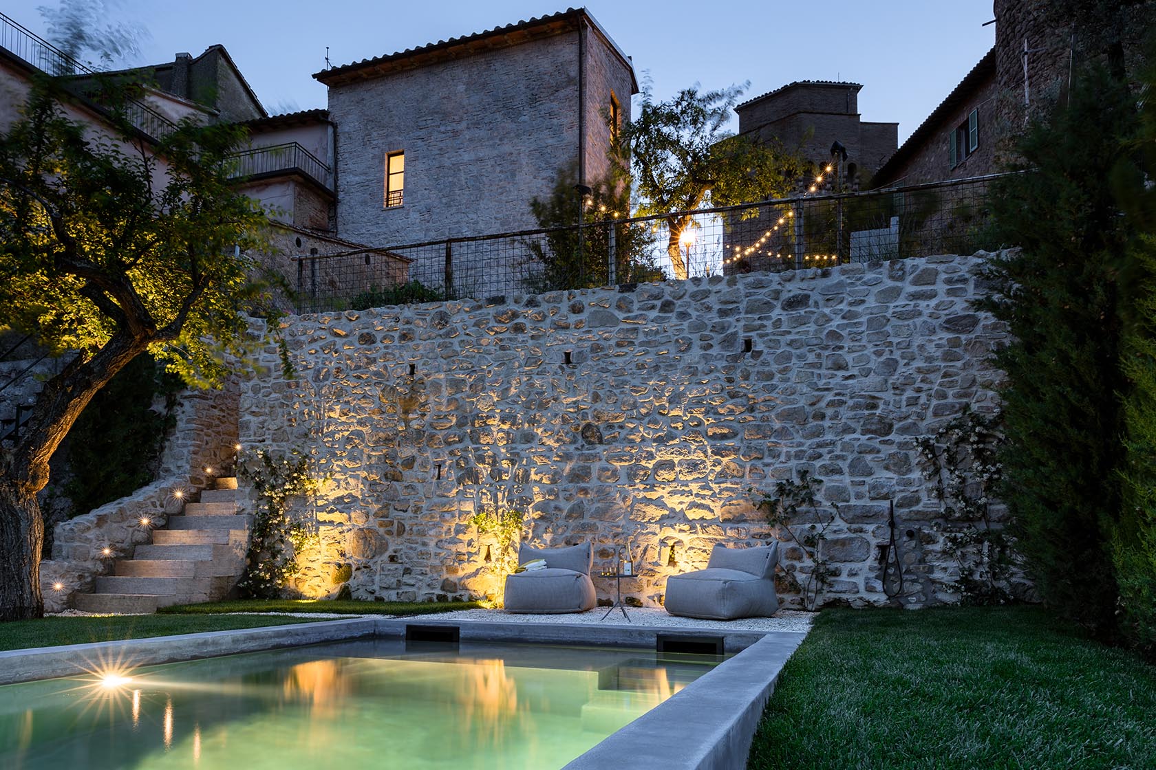 Perfect Hideaways illuminated stone courtyard with a tranquil pool at dusk, Umbria Cottage, Collazzone