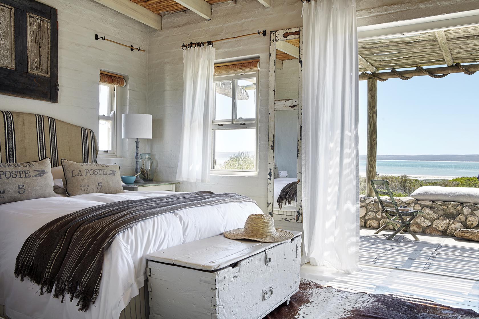 Perfect Hideaways - A serene bedroom decorated in soft whites and natural textures, opening onto a shaded deck with sweeping views of the turquoise lagoon Seagull Cottage_Churchhaven_West Coast_Western Cape_South Africa