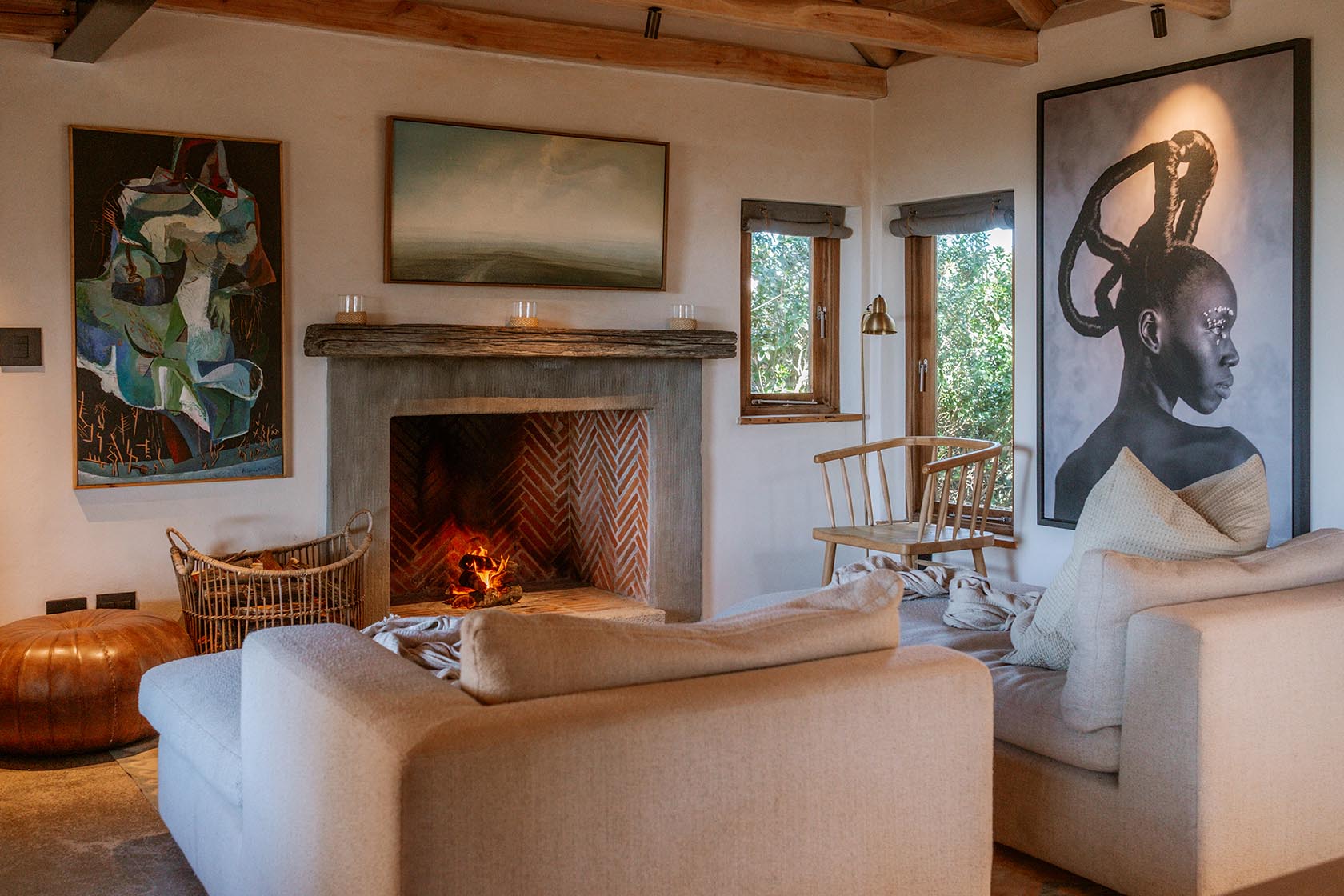 Perfect Hideaways- Warm, inviting living room with a central fireplace, soft neutral sofas, timber ceiling beams, woven textures and large contemporary artworks creating a relaxed coastal interior, Yellowwood Cottage, Churchhaven, Western Cape, South Africa