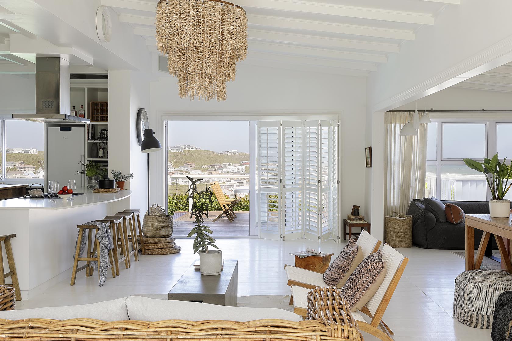 Perfect Hideaways - Open-plan living area with white interiors, woven textures and lounge seating, flowing seamlessly from the kitchen to a deck with coastal village and ocean views beyond Cape Cottage_Yzerfontein_West Coast_Western Cape_South Africa
