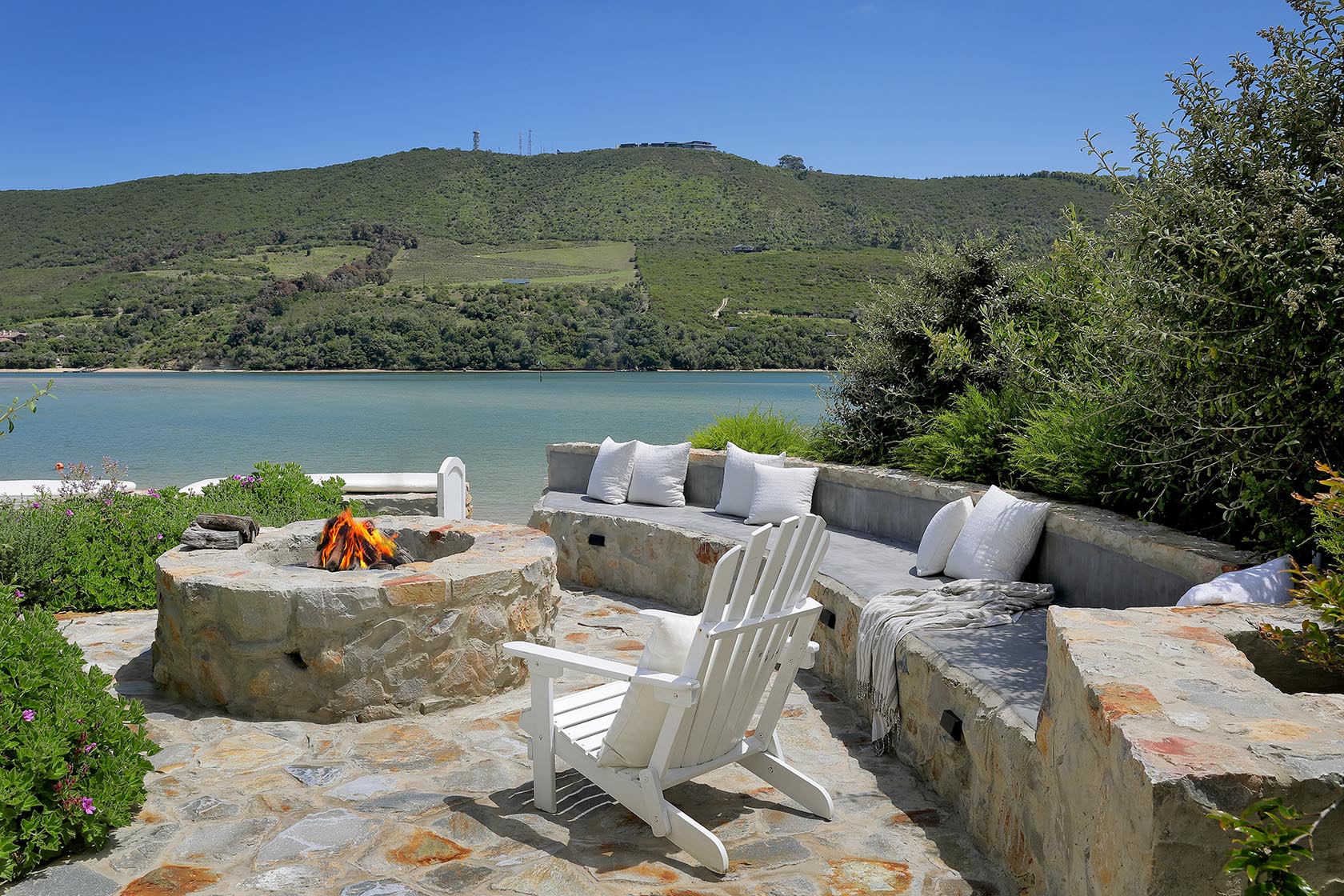Perfect Hideaways: Lagoon-side firepit terrace with a curved built-in bench and Adirondack chairs for sunset gatherings, Knysna, Tides Reach