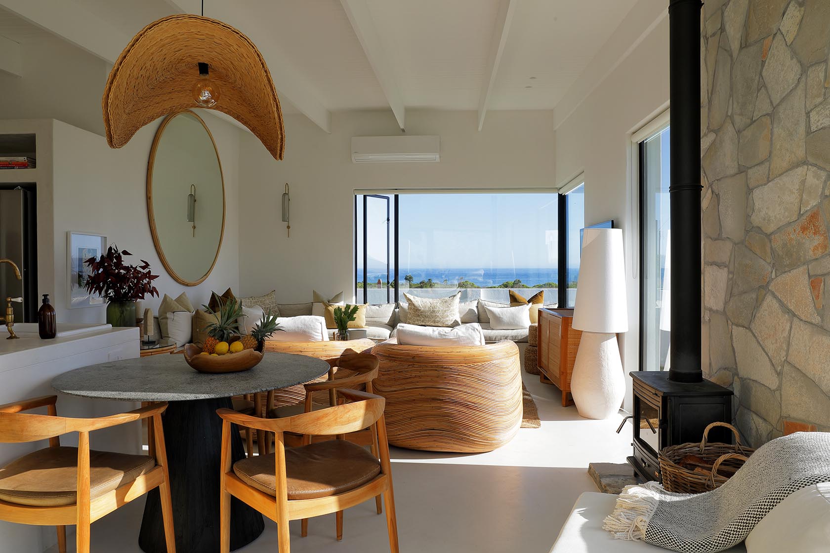 Perfect Hideaways airy dining and living space with wood-burning fireplace, sculptural lighting and sweeping ocean views through floor-to-ceiling glass, Soudt, Kleinmond