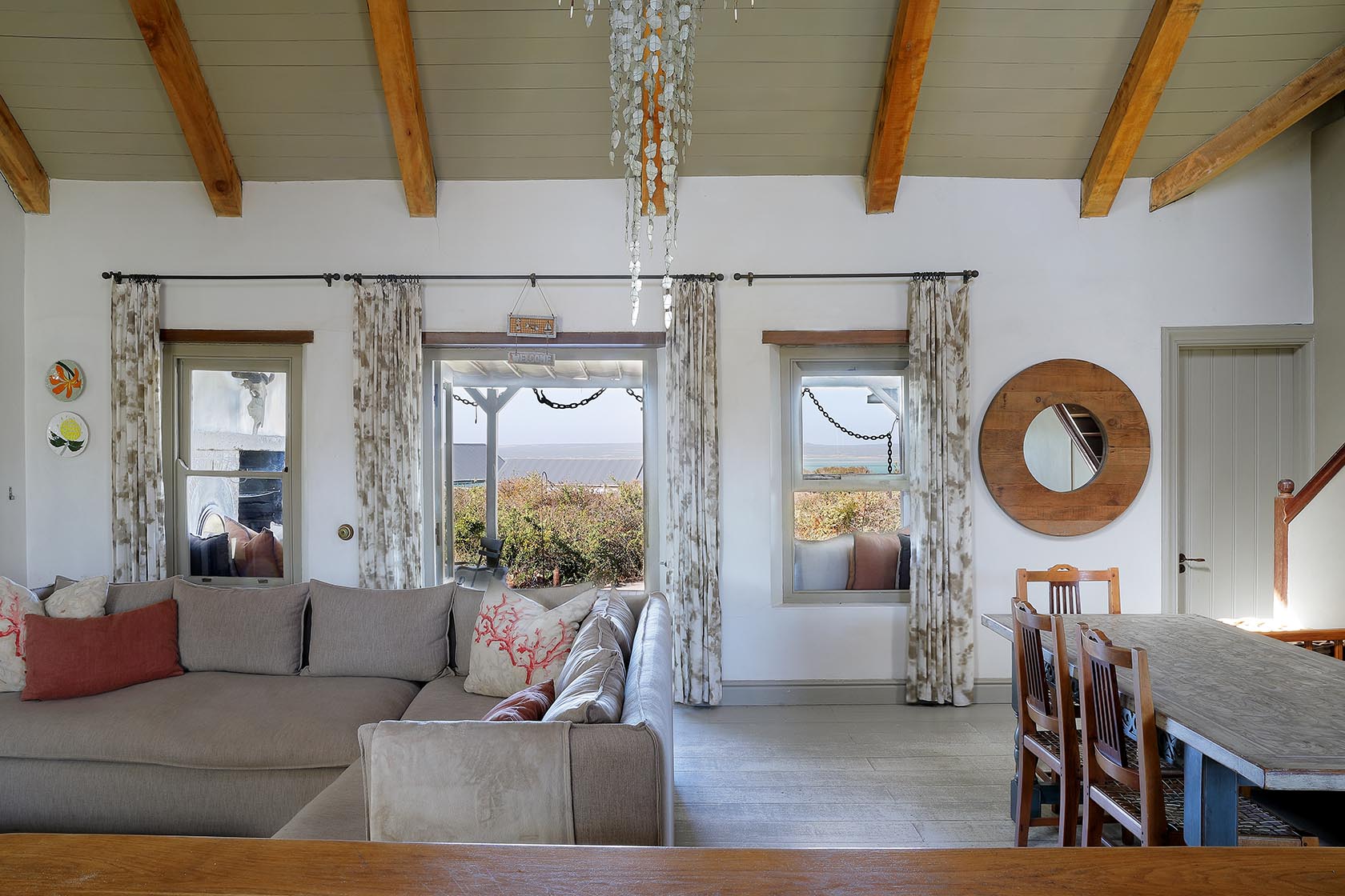 Perfect Hideaways–Bright living room with vaulted beams, large windows facing the fynbos, a spacious corner sofa, and a wooden dining table. Church Cottage, Churchhaven, South Africa