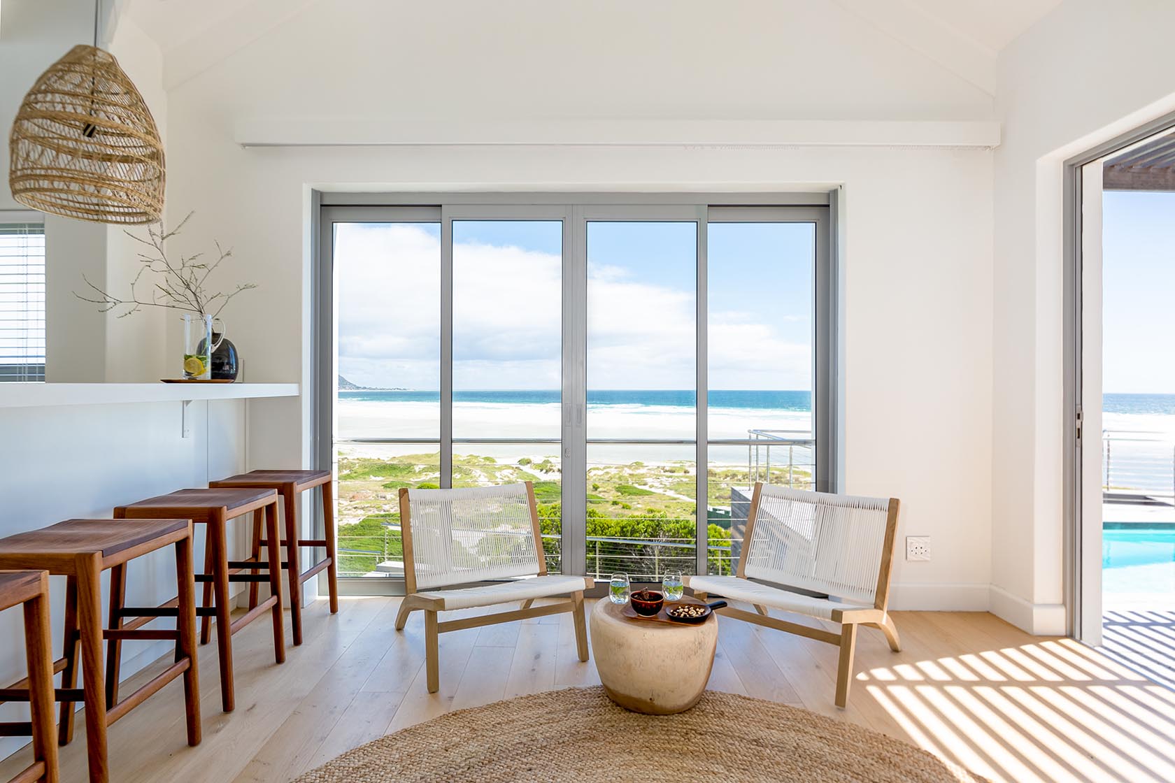 Perfect Hideaways - Stylish indoor seating area with bar stools and sliding doors framing sweeping views of Noordhoek beach and the Atlantic Ocean Noordhoek Seashore_Noordhoek_Southern Peninsula_Cape Town_Western Cape_South Africa