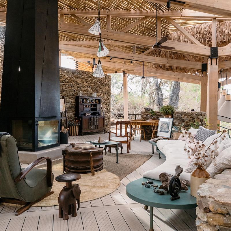 Perfect Hideaways – a wide view of two contemporary tented suites with sweeping canvas roofs, glass walls, and elevated decks overlooking trees and natural bush, with a sunken outdoor lounge and firepit in the foreground at Saseka Tented Camp, Thornybush Game Reserve, Mpumalanga South Africa