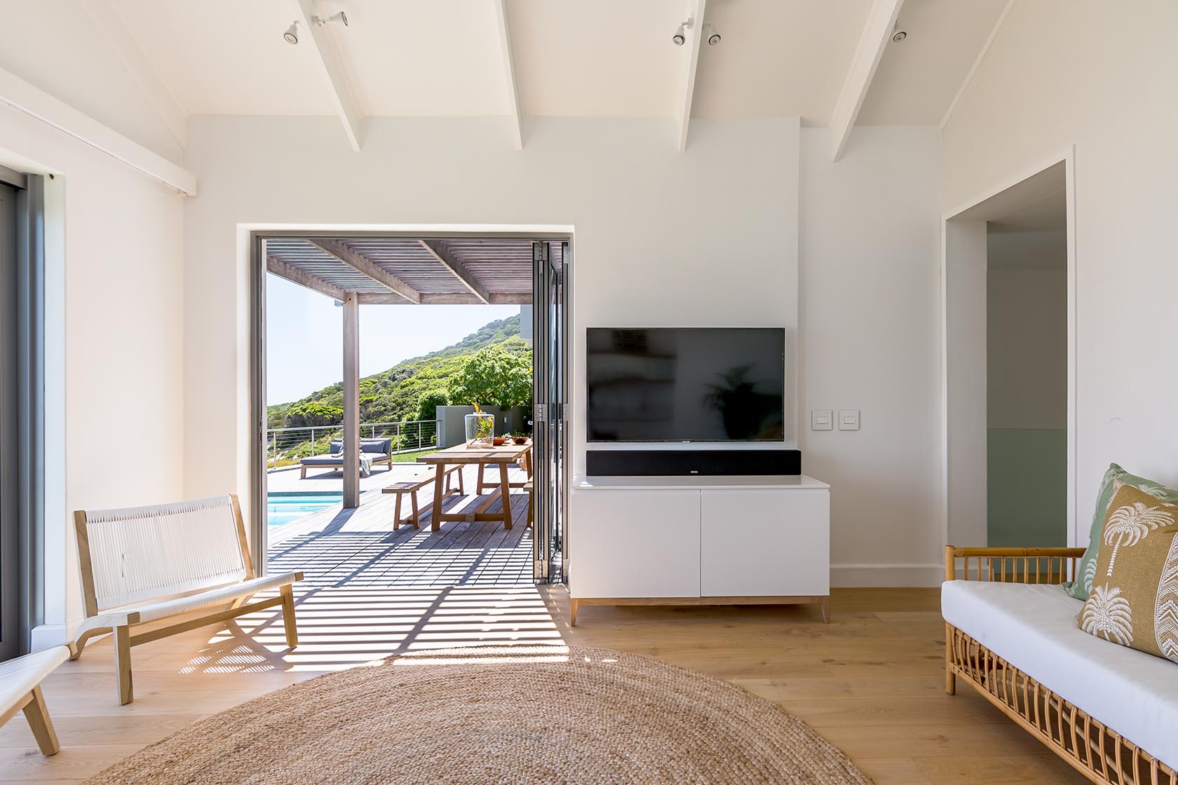 Perfect Hideaways - Minimalist lounge with open doors leading to a shaded deck, pool and lush hillside surroundings Noordhoek Seashore_Noordhoek_Southern Peninsula_Cape Town_Western Cape_South Africa