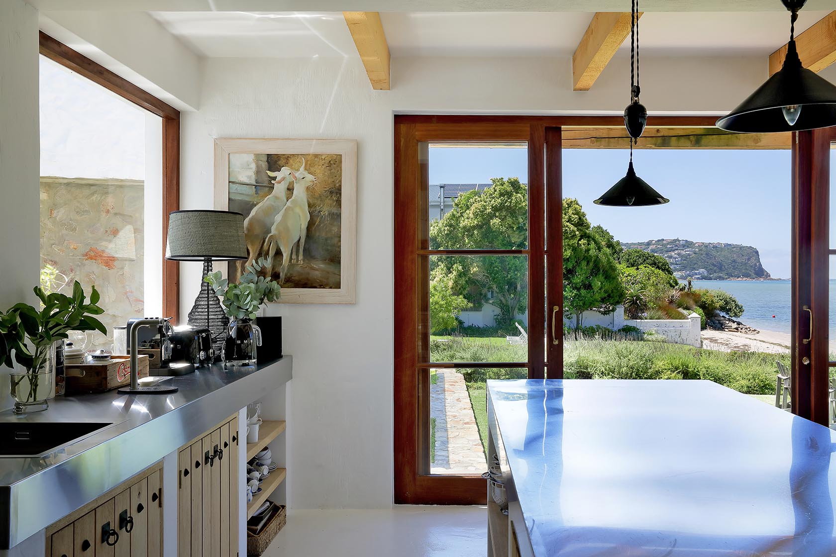 Perfect Hideaways: Coffee station and glossy island beneath black pendants, doors opening to garden, dunes and the Knysna Heads, Knysna, Tides Reach