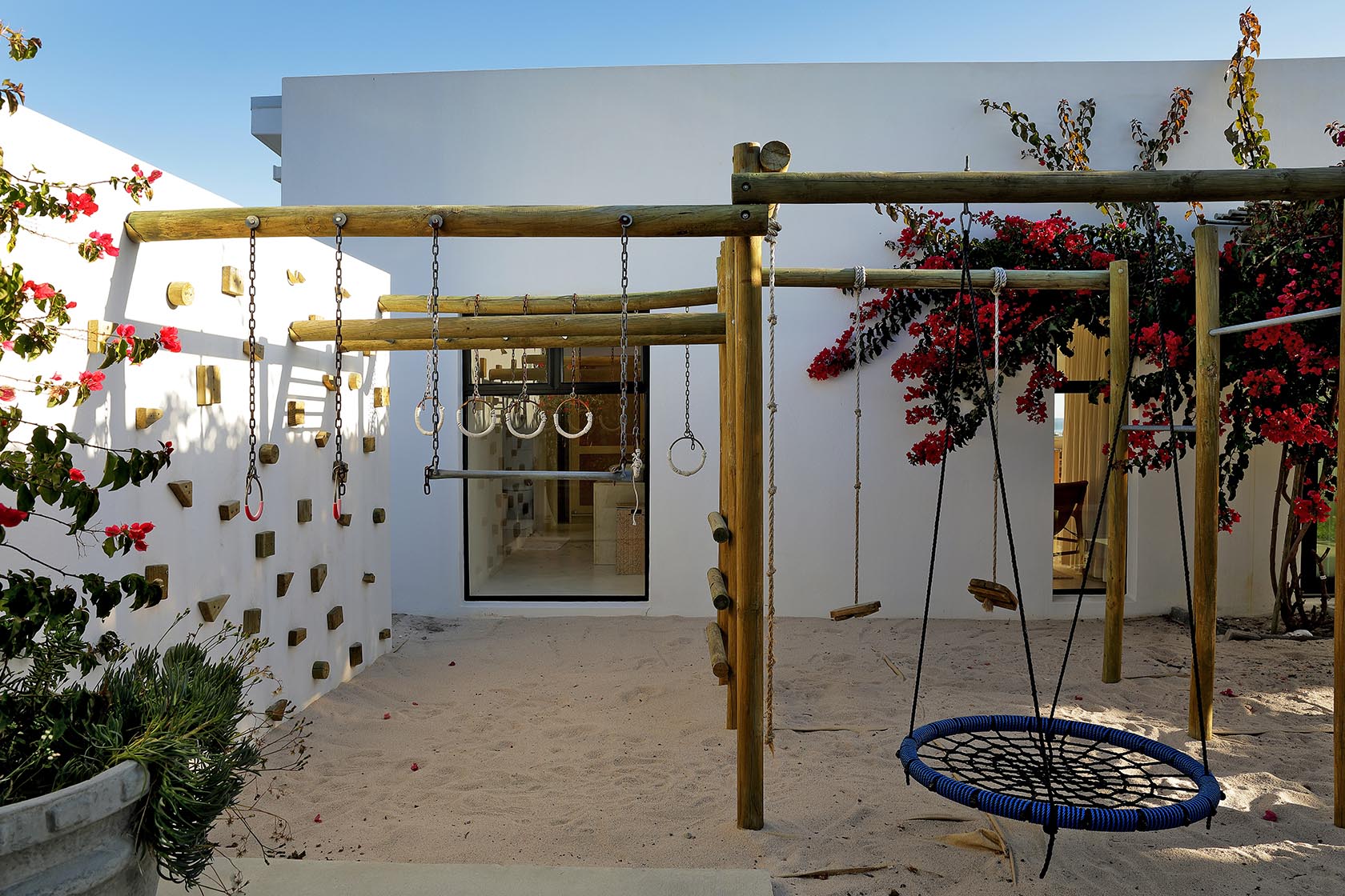 Perfect Hideaways outdoor children’s play area with wooden jungle gym set against whitewashed walls and blooming bougainvillea, Soudt, Kleinmond