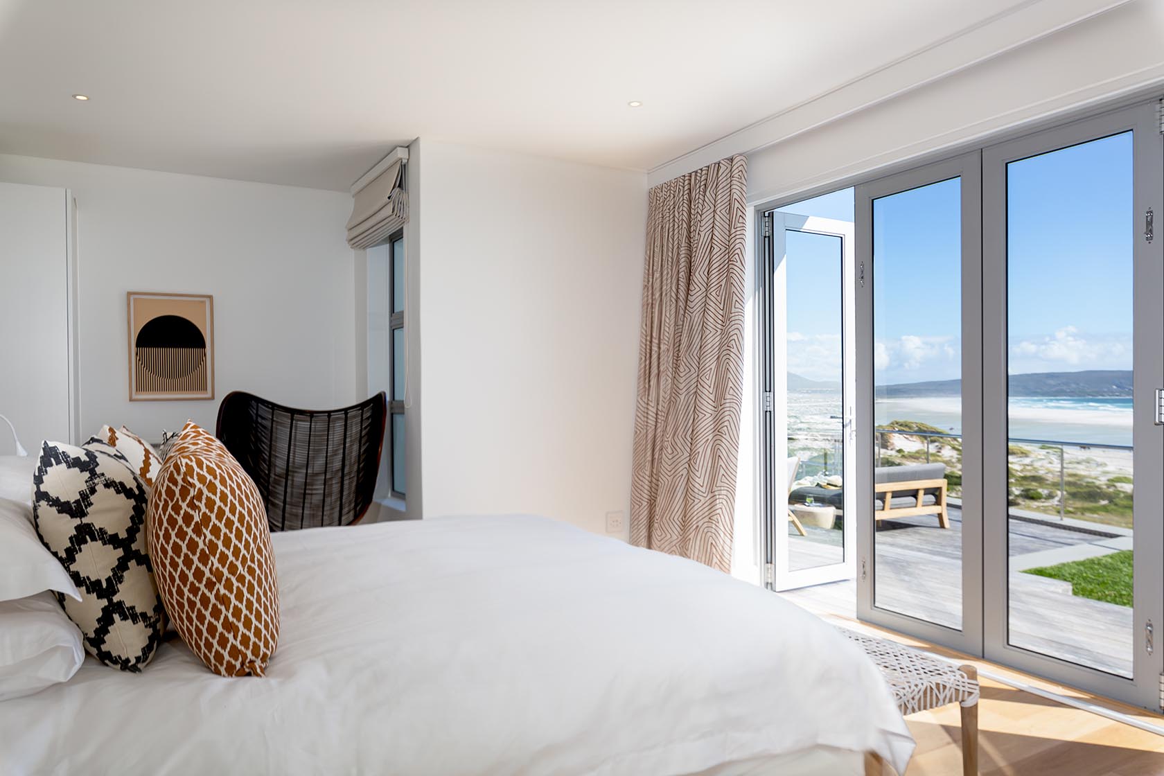 Perfect Hideaways - Bright coastal bedroom with plush white bedding, textured cushions and sliding glass doors opening onto a private deck with ocean views Noordhoek Seashore_Noordhoek_Southern Peninsula_Cape Town_Western Cape_South Africa