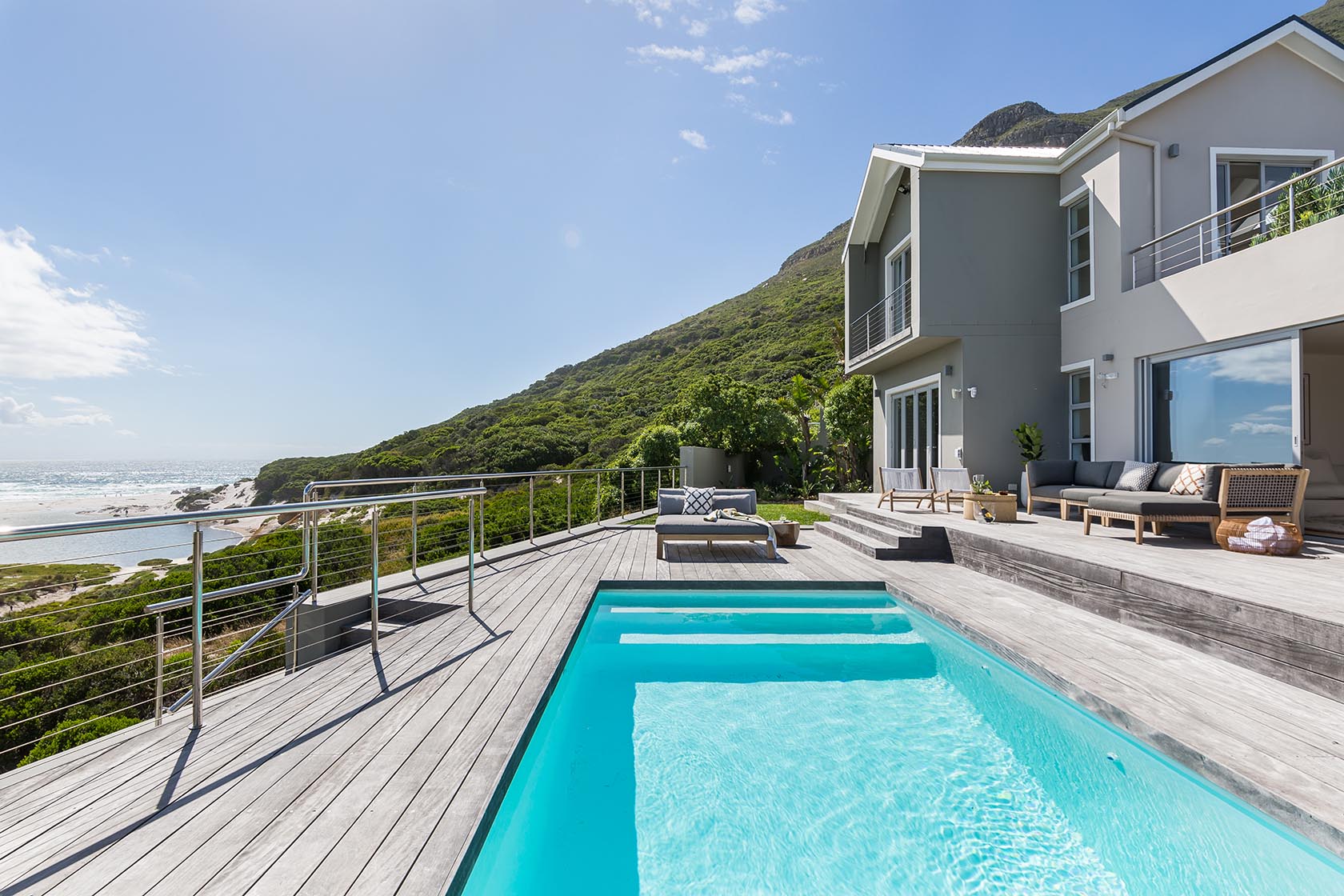 Perfect Hideaways - Expansive wooden pool deck with outdoor lounge seating and contemporary coastal architecture framed by mountain views Noordhoek Seashore_Noordhoek_Southern Peninsula_Cape Town_Western Cape_South Africa