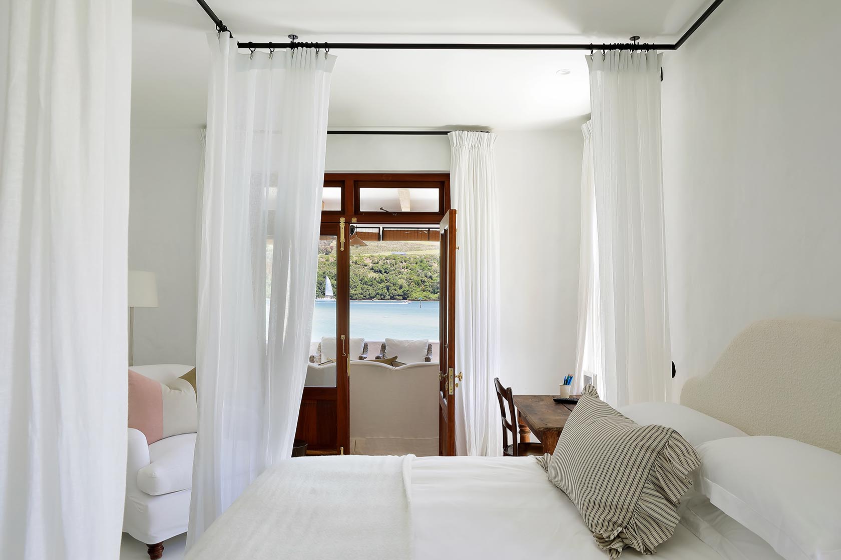 Perfect Hideaways: Calm bedroom in soft neutrals with rustic console desk, armchair and doors to a lagoon‑facing terrace, Knysna, Tides Reach