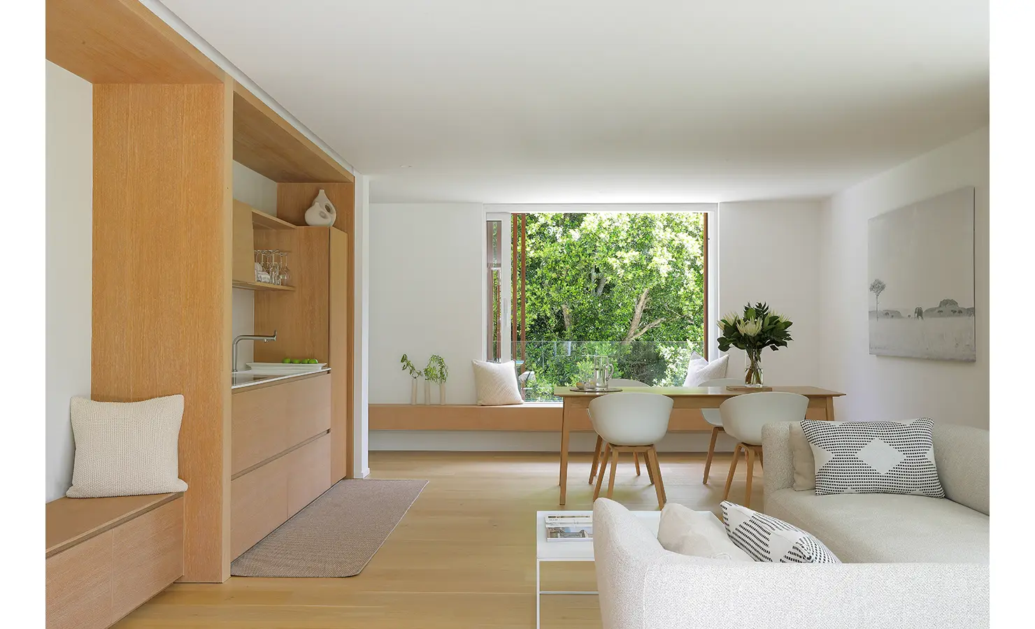 Perfect Hideaways A calm open-plan dining and kitchenette area with light wood cabinetry, simple décor, and a wide picture window framing lush green treetops Pure Living, Bishopscourt