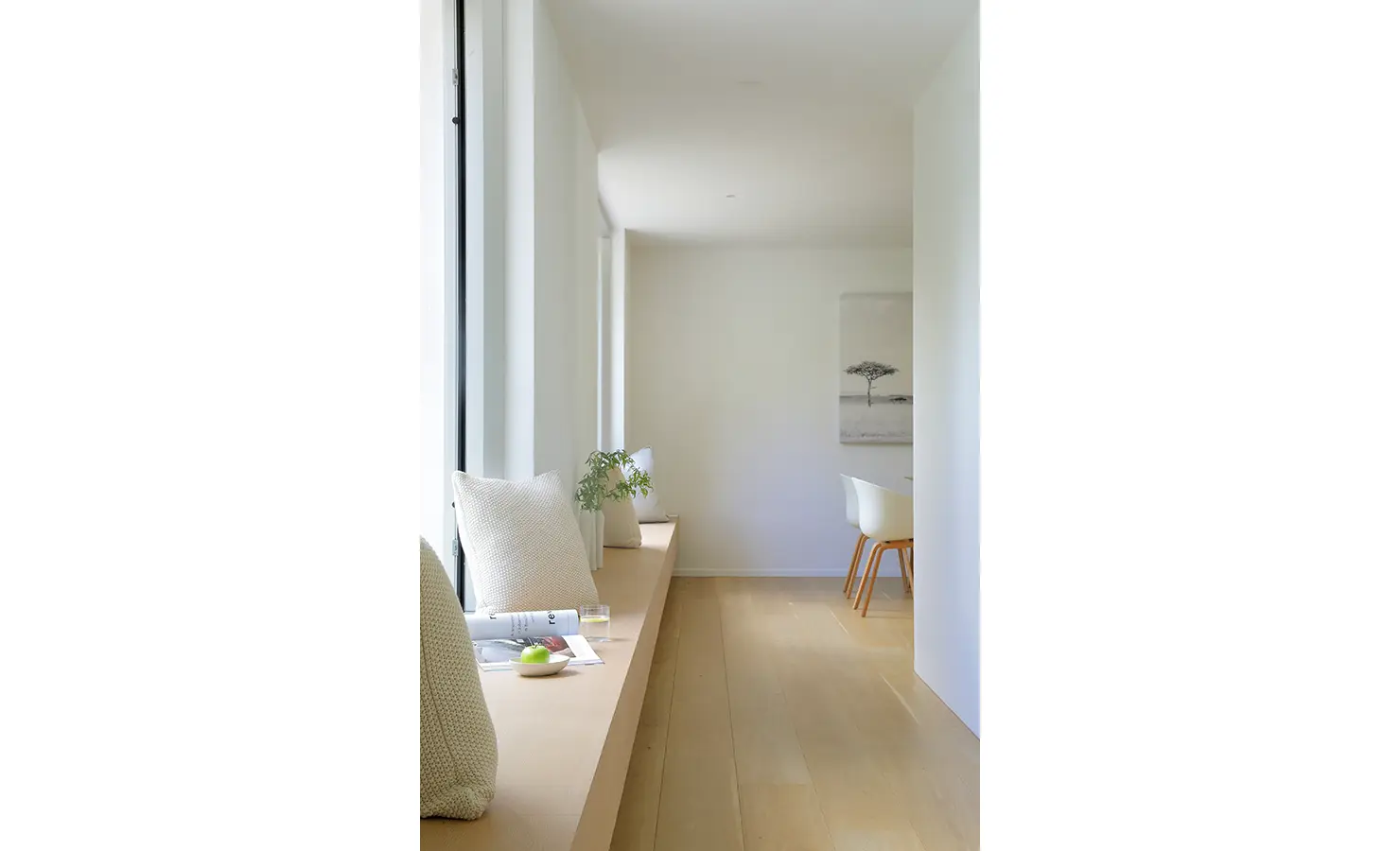 Perfect Hideaways A bright passageway with a long built-in timber bench layered with soft neutral cushions, looking out to greenery through tall windows Pure Living, Bishopscourt