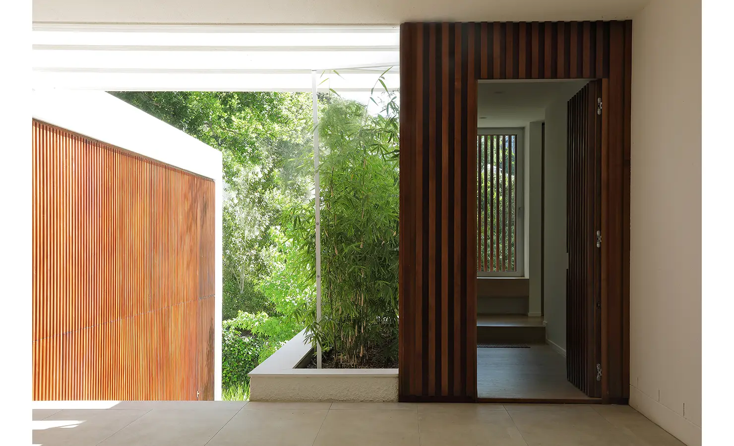 Perfect Hideaways A modern entryway with rich vertical timber slats opens to a garden courtyard filled with bamboo and natural light Pure Living, Bishopscourt