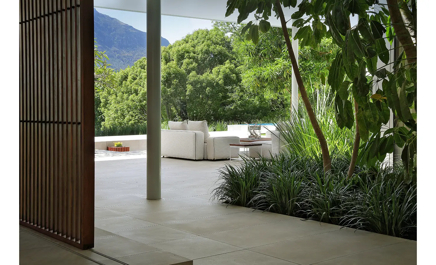 Perfect Hideaways A tranquil outdoor living area seen through a shaded walkway, with soft white sofas overlooking lush gardens and dramatic mountain views Pure Living, Bishopscourt