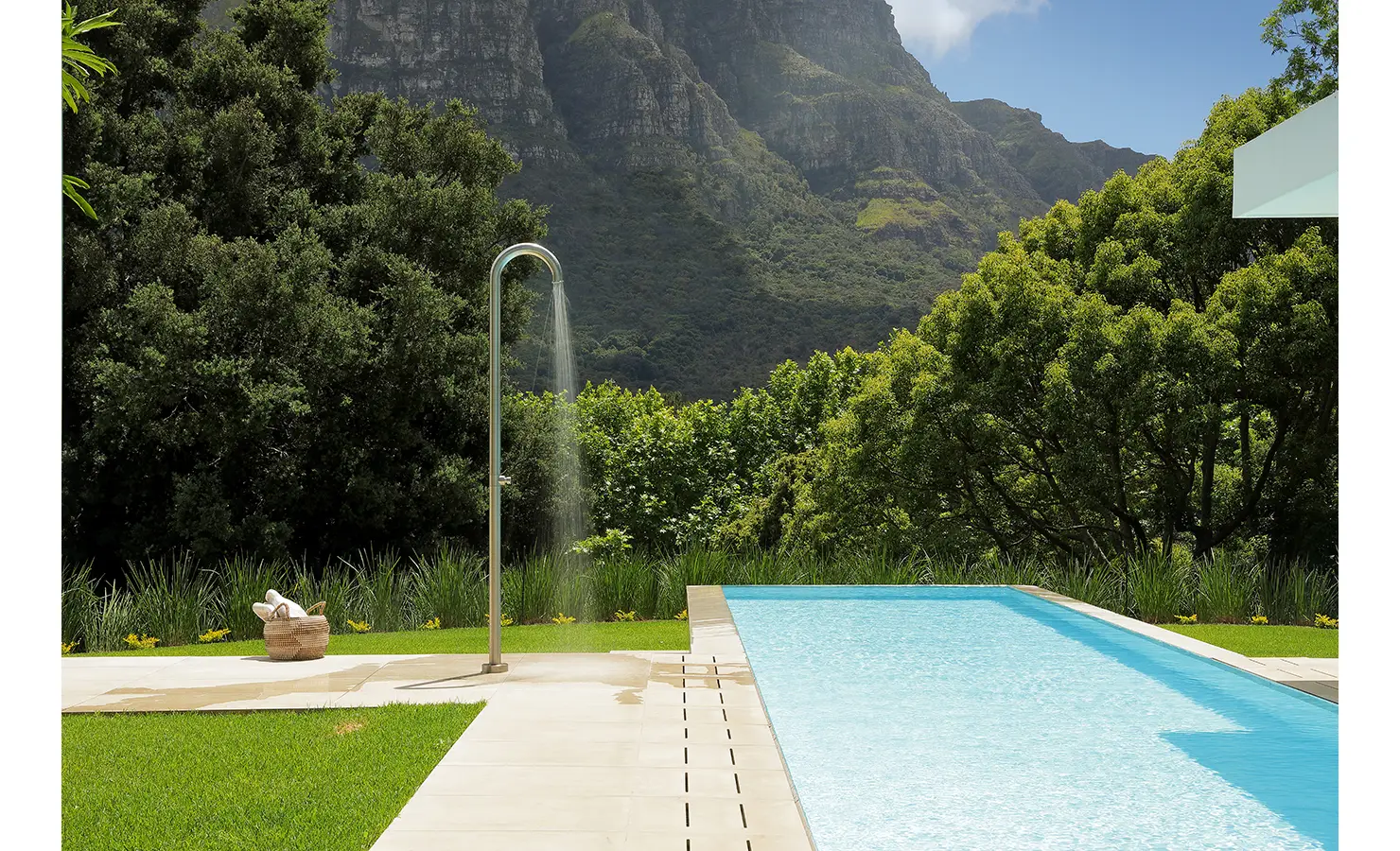 Perfect Hideaways A sparkling lap pool beside manicured lawns and an outdoor shower, backed by dense greenery and towering mountain cliffs Pure Living, Bishopscourt