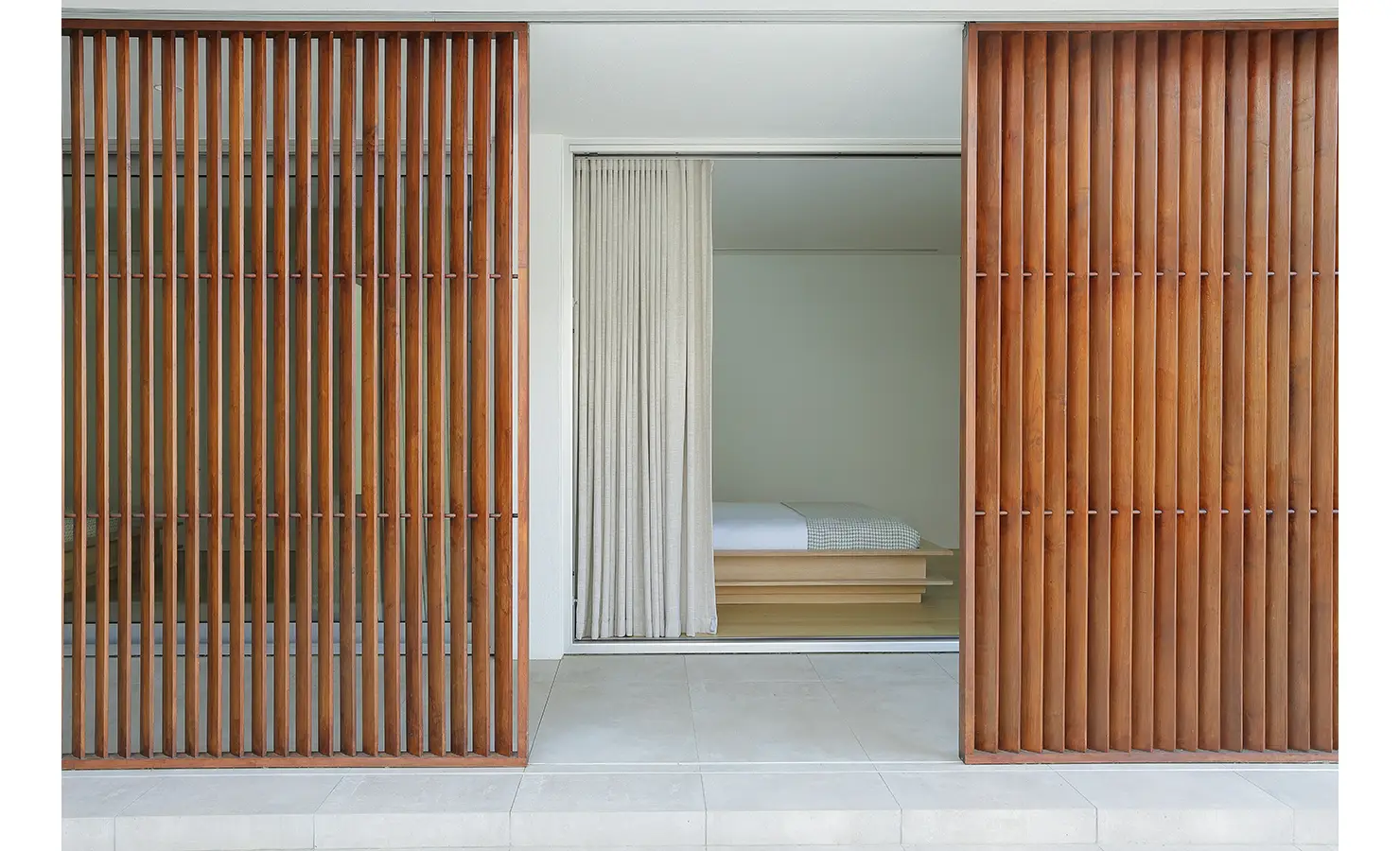 Perfect Hideaways A serene bedroom entrance framed by rich timber slatted screens opens to a minimalist space with soft neutral bedding Pure Living, Bishopscourt