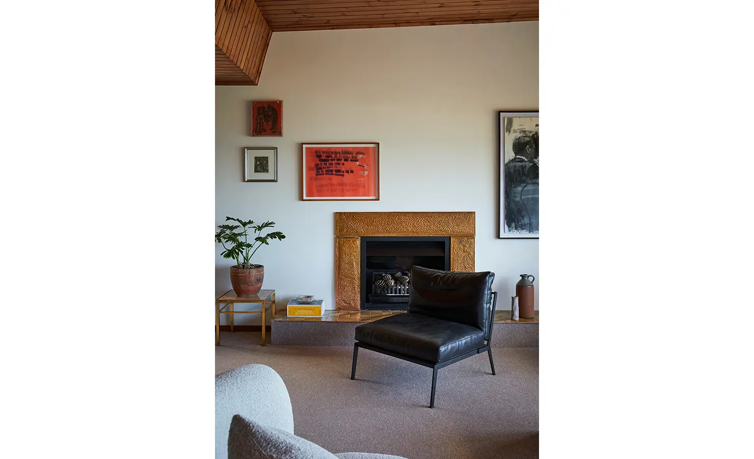 Perfect Hideaways a cosy corner with a black leather lounge chair facing a textured stone fireplace, surrounded by curated artwork, indoor plants, and warm-toned decor elements Camps Bay, The Liminal