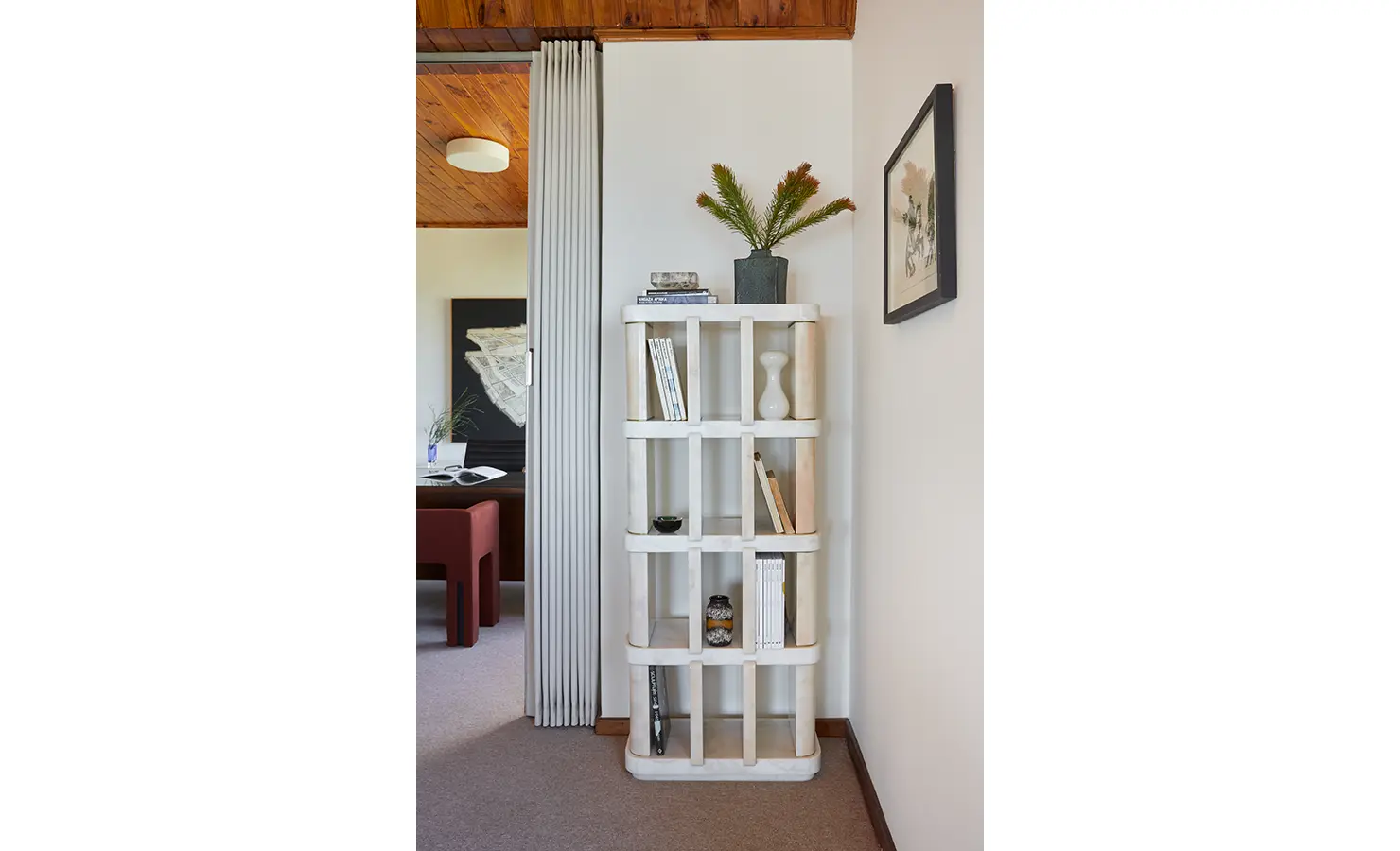 Perfect Hideaways a sculptural white shelving unit styled with books and ceramics, framed by soft wall art and a glimpse into the adjoining room featuring modern artwork and warm timber accents Camps Bay, The Liminal