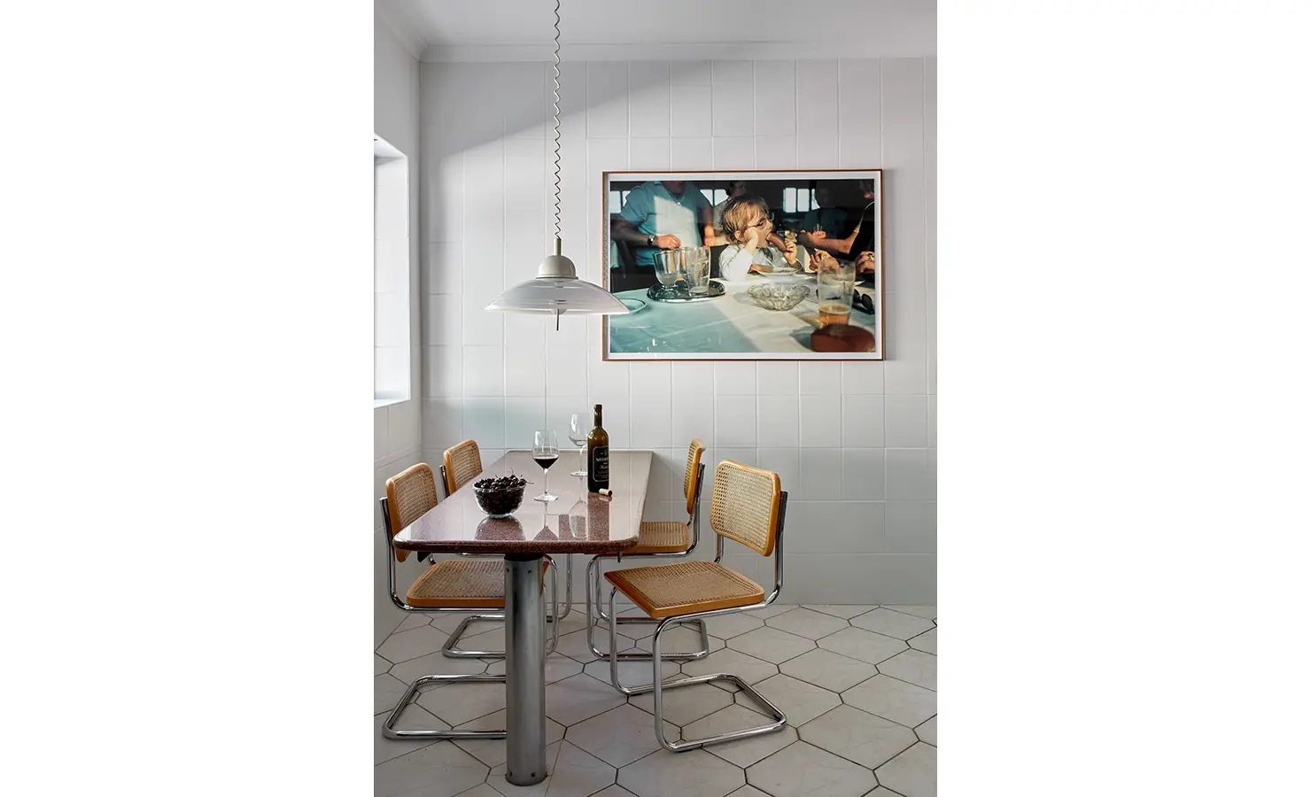 Perfect Hideaways a retro-style breakfast nook with a glossy maroon table, cane-and-chrome chairs, pendant lighting, and a nostalgic photograph hanging above a bottle of wine and two glasses Camps Bay, The Liminal