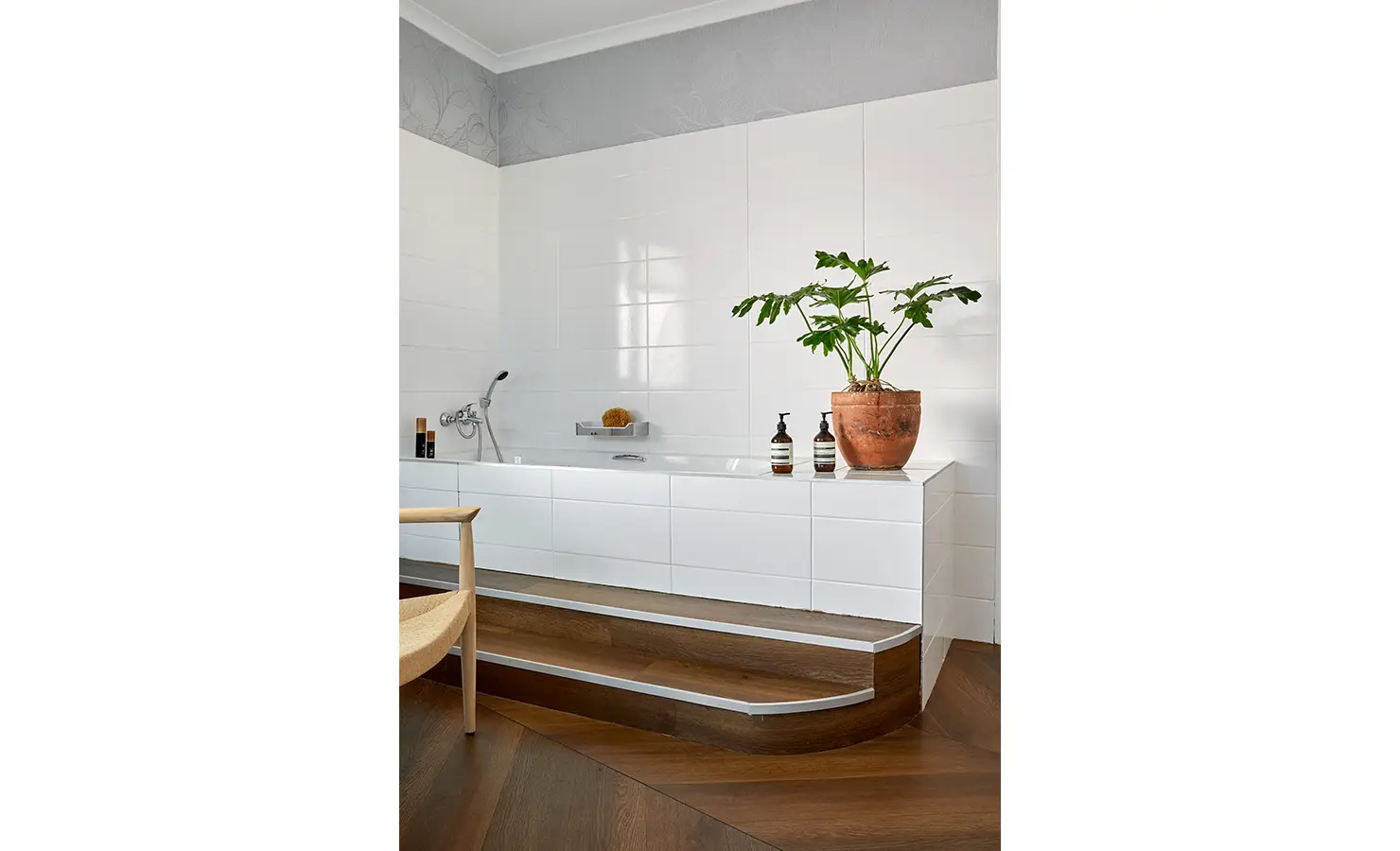 Perfect Hideaways a spacious bathroom with raised white tiled bathtub, warm wooden steps, large terracotta potted plant, and minimalist fixtures adding a serene spa-like feeling Camps Bay, The Liminal