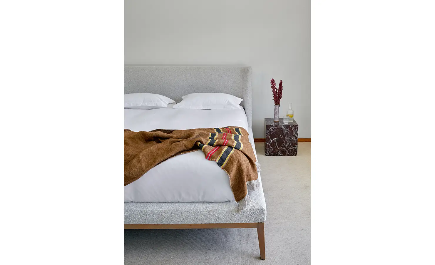 Perfect Hideaways a minimal bedroom detail featuring a textured upholstered bed, soft neutral bedding, a warm throw blanket, and a marble side table with sculptural decor Camps Bay, The Liminal