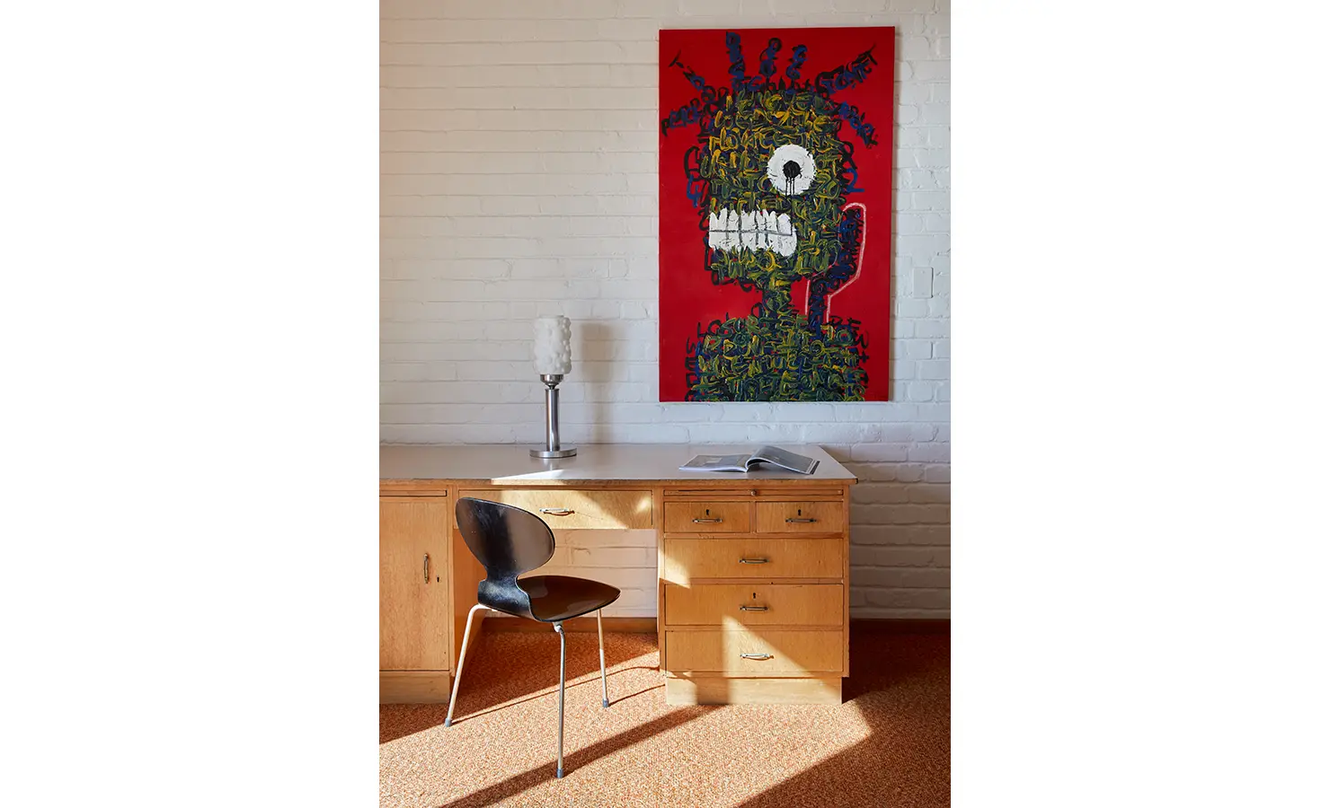 Perfect Hideaways a character-filled workspace with a vintage wooden desk, sleek black chair, sculptural table lamp, and a striking red artwork featuring an expressive figure on a brick wall Camps Bay, The Liminal