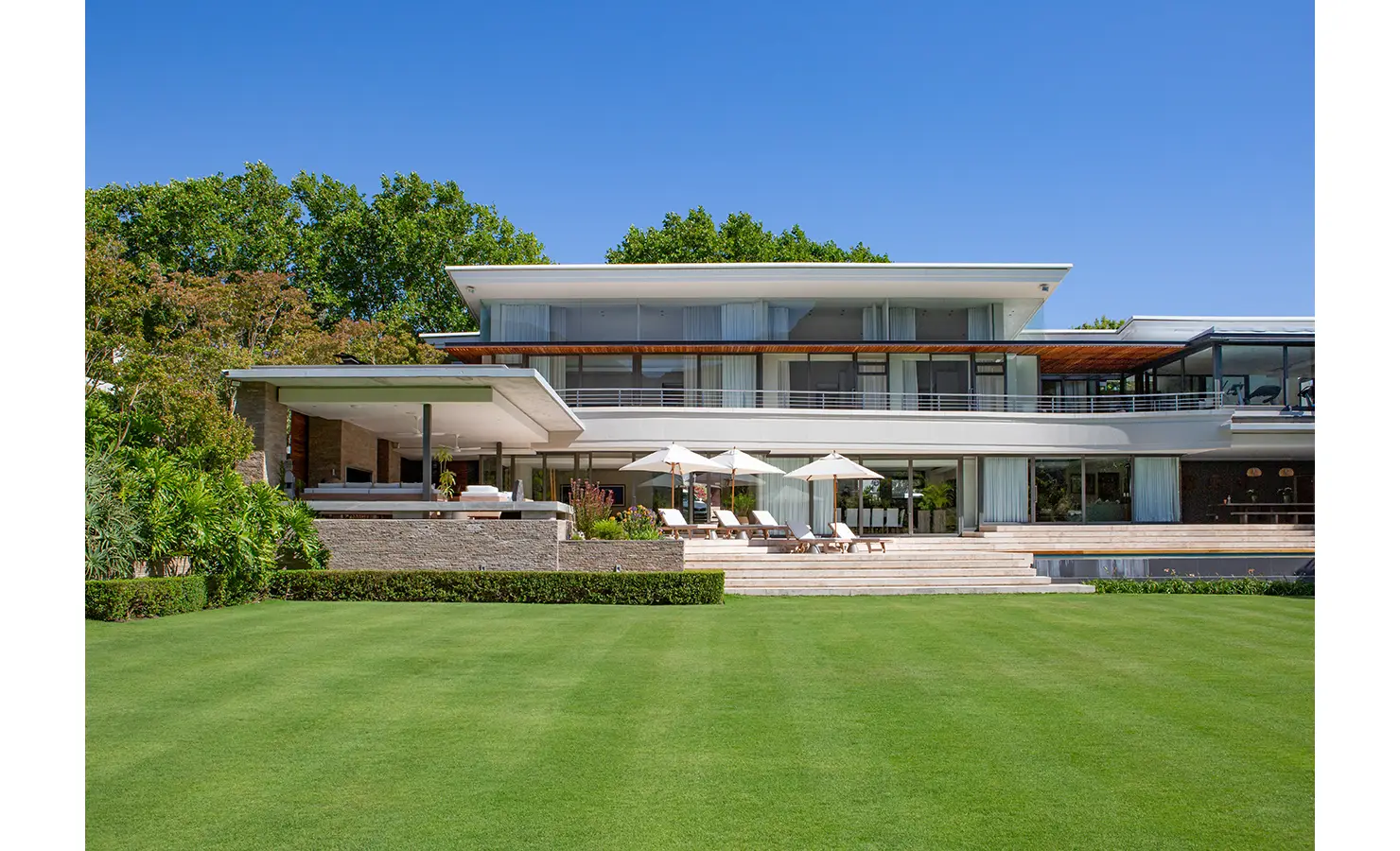 Perfect Hideaways contemporary multi-level villa exterior with expansive terraces, manicured lawn and sun loungers overlooking lush gardens, Bishopscourt, Botanical Villa