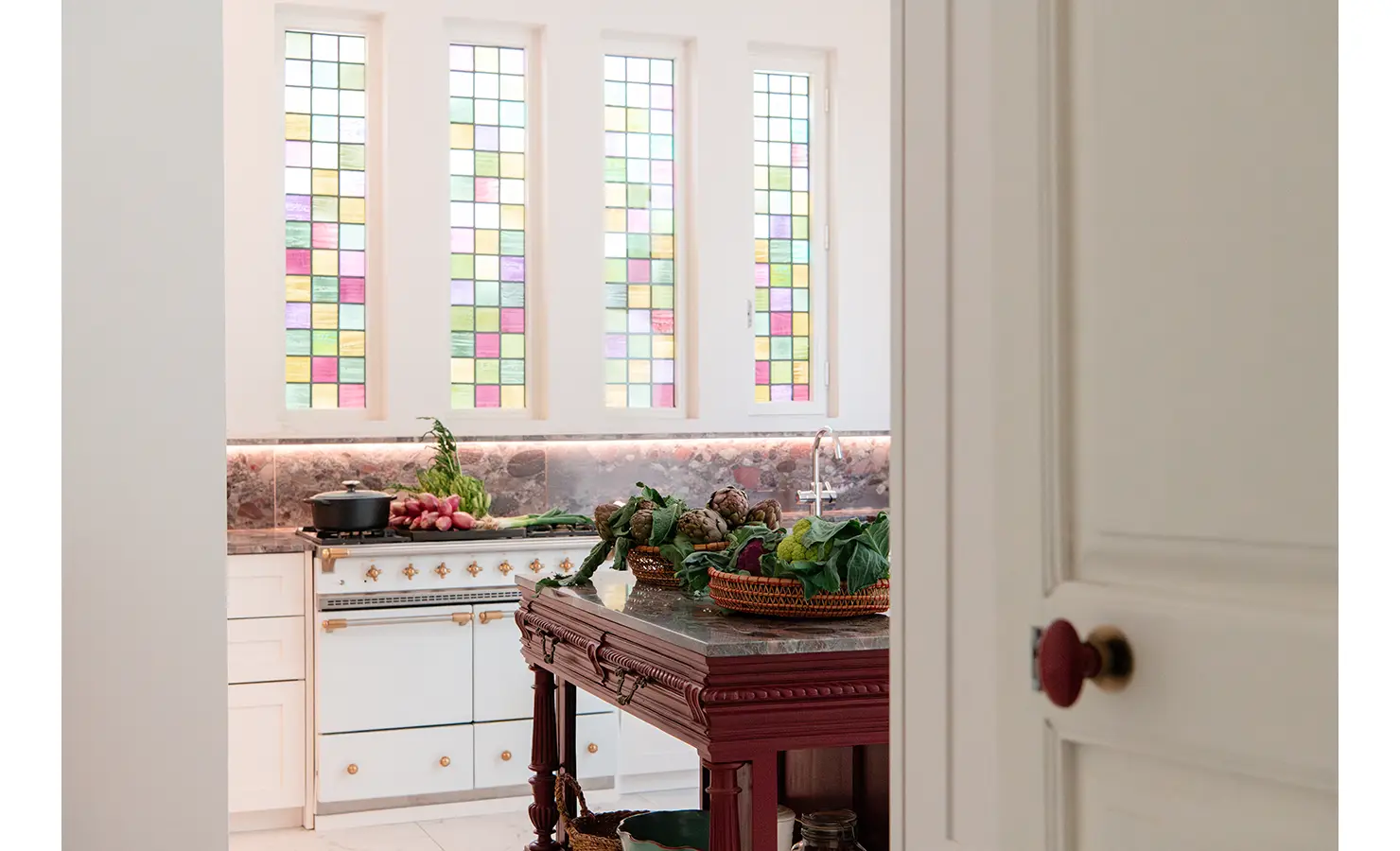 Perfect Hideaways bright kitchen with colourful stained-glass windows, marble worktops, classic white cabinetry, and a wooden island topped with fresh produce, Nardo House, Lecce