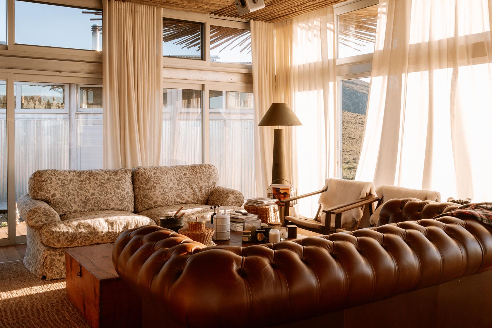 Perfect Hideaways cosy lounge with leather sofa, soft furnishings and floor-to-ceiling windows, Jackals Rest, Montagu.