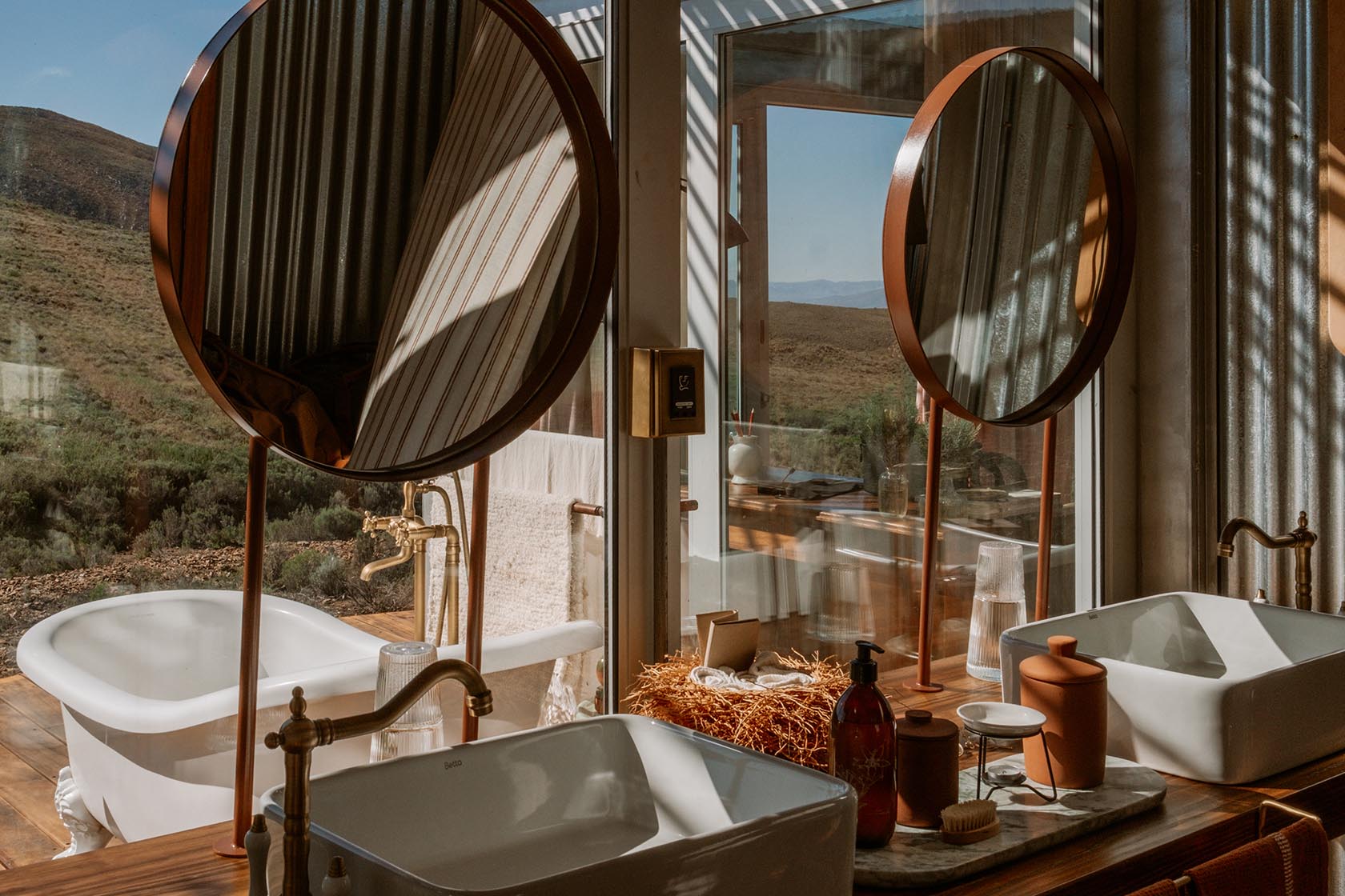 Perfect Hideaways stylish bathroom with twin basins, freestanding bath and panoramic Karoo views framed by warm natural light, Jackals Rest, Montagu.